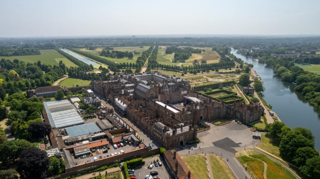 Breathtaking aerial view of historic Hampton Court Palace surrounded by lush gardens.